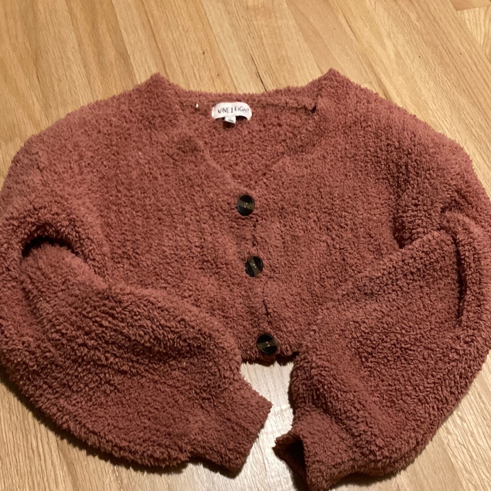 a pink cropped sweater with buttons